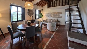 Amplia sala de estar con una mesa de comedor, sillas, un sofá y una escalera.