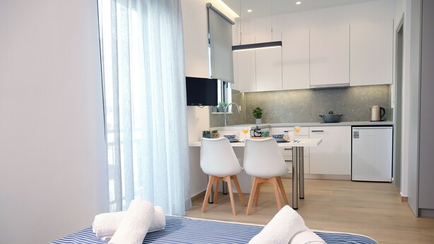A modern hotel room with a bed, a small kitchenette, and a dining area. - Economic Studio B10 (Iraklio)