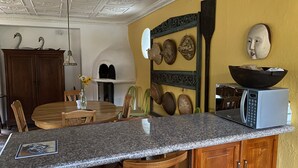 Une cuisine dotée d’un plan de travail en granit, de meubles en bois, d’un four à micro-ondes et d’œuvres d’art décoratives murales.