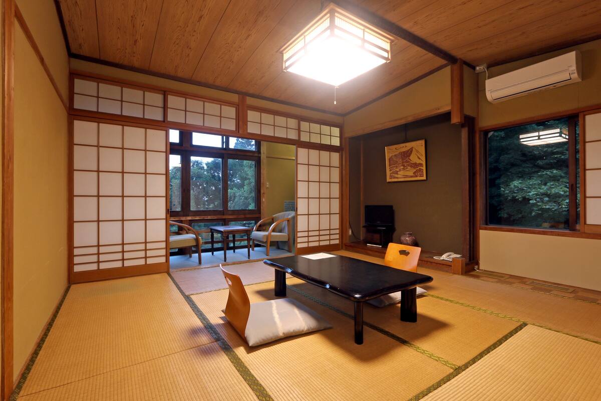 A traditional Japanese room with tatami flooring, a low table, and sliding doors.