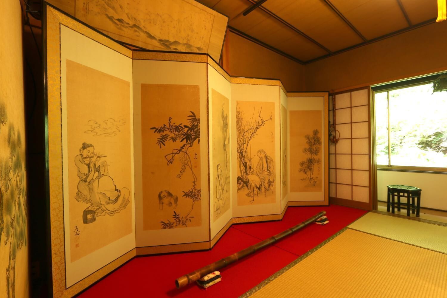 A traditional Japanese room with tatami flooring, a shoji screen, and calligraphy scrolls.
