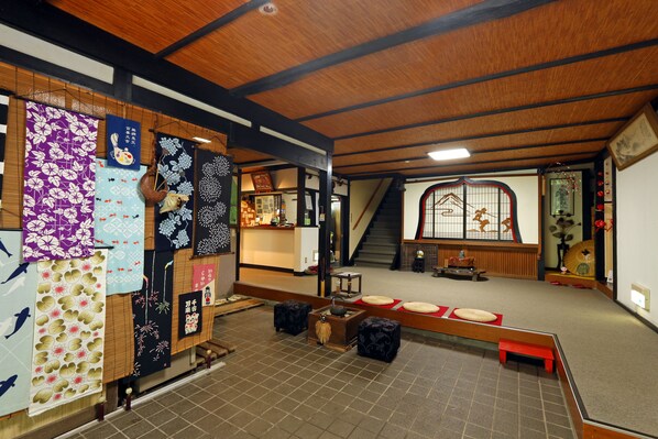 A traditional Japanese interior with tatami flooring, shoji screens, and a wooden beam ceiling.