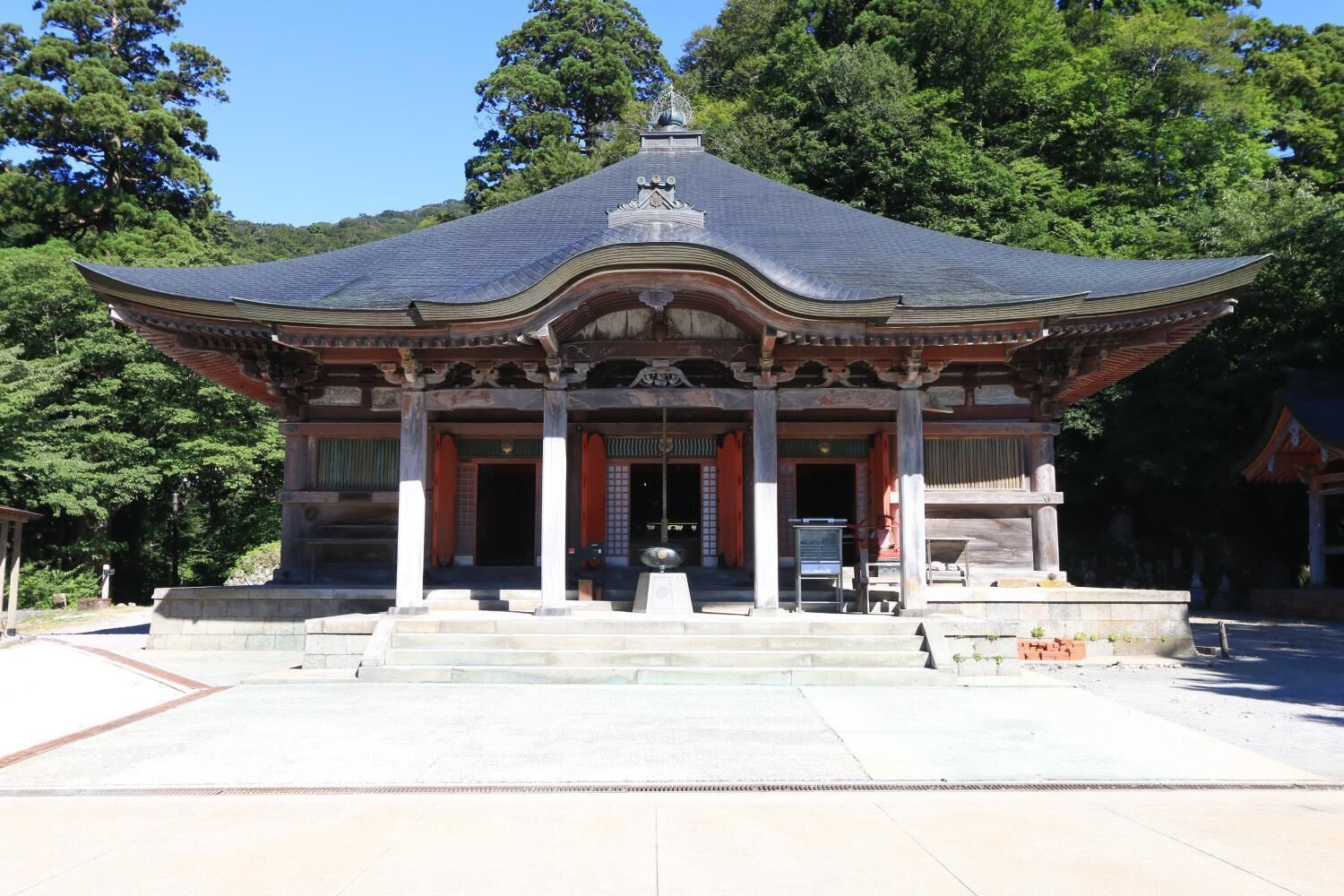Un edificio japonés tradicional con techo curvo, entrada central y base de piedra.