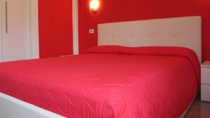 A bed with a red bedspread in a room with red walls and white headboard. - Palinuro home 'Donna Antonia' (Palinuro)