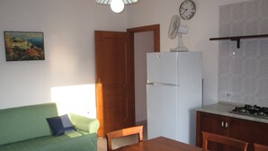 A compact kitchen with a refrigerator, stove, and dining area. - Palinuro home 'Donna Antonia' (Palinuro)