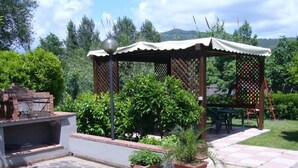 An outdoor patio area with a barbecue grill, potted plants, and a wooden pergola. - Palinuro home 'Donna Antonia' (Palinuro)