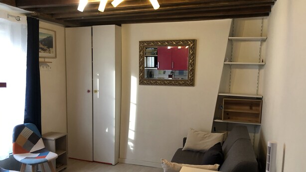 Un espace de vie compact comprenant un canapé, une petite table, une chaise, un meuble et un miroir accroché au mur.