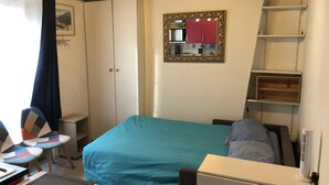 Une chambre à coucher comprenant un lit, un bureau, une chaise, une petite table, un miroir et une armoire.