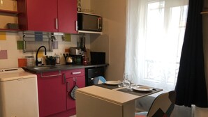 Une cuisine compacte équipée d’un four à micro-ondes, d’un grille-pain et d’un évier. Un coin repas avec une table et des chaises est également à disposition.