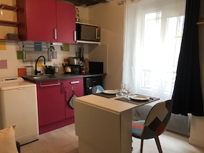 A compact kitchen with a microwave, toaster, and sink. There is a dining area with a table and chairs. - Beautiful studio, 1 or 2 people (Paris)
