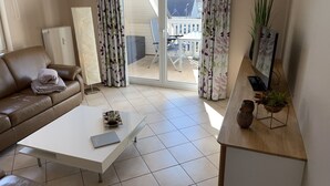 A living room with a brown leather sofa, a white coffee table, and a wooden side table with a plant. - COMPLETELY RENOVATED! NO PRICE INCREASE FOR 2026+2027 !!! BEACH CHAIR INCLUDED! (Binz)