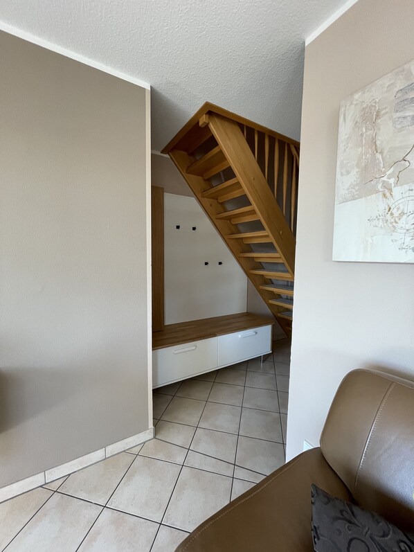 Une pièce avec un escalier en bois, une armoire blanche et un canapé en cuir marron.