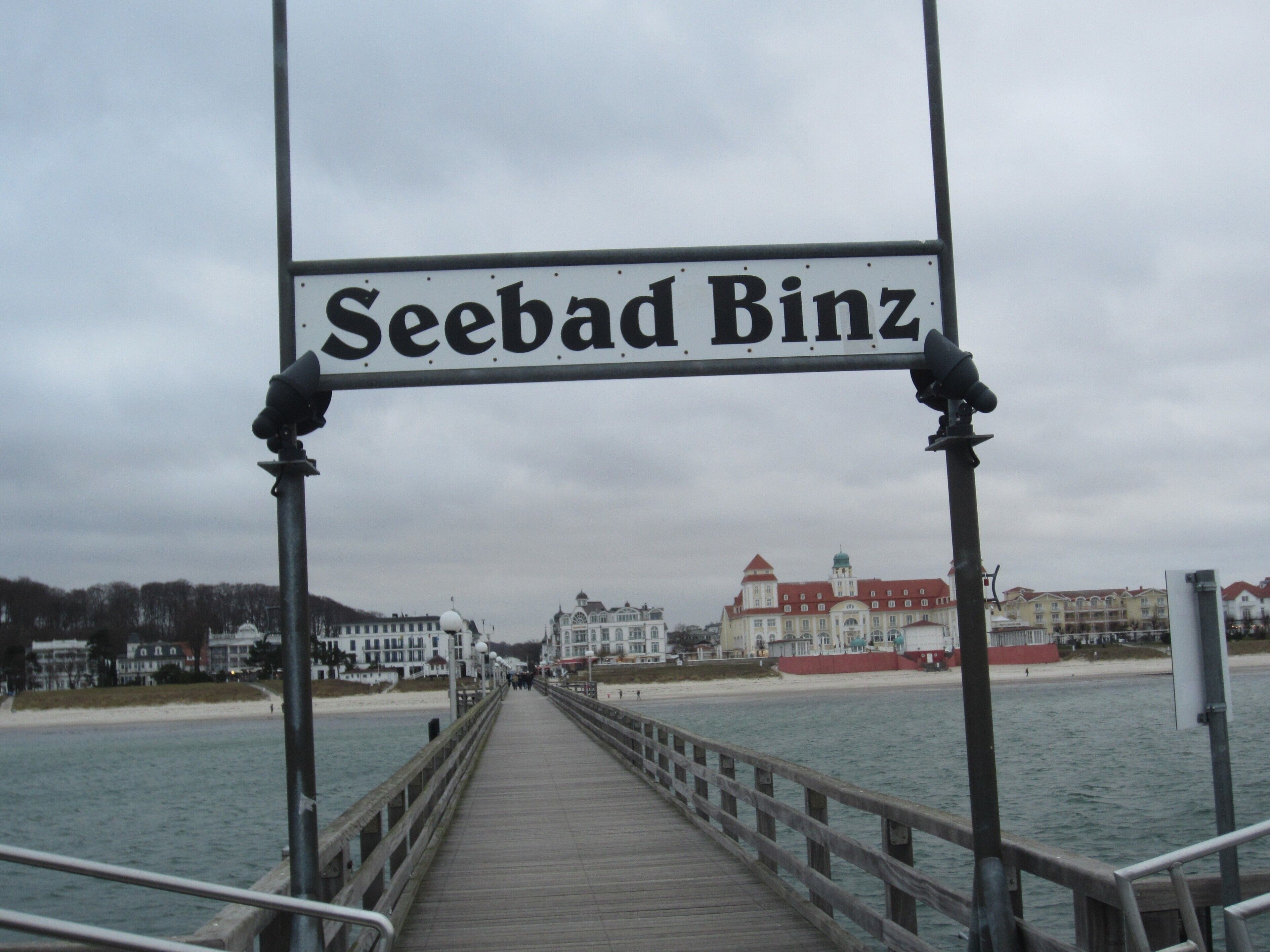 Un muelle que conduce a Seebad Binz, con vistas a edificios y una playa al fondo.