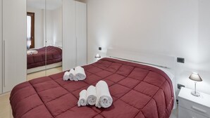 Ein Hotelzimmer mit einem großen Bett, einem Kleiderschrank, einem Nachttisch und einem Spiegel.