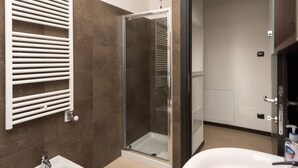 Ein modernes Badezimmer mit einer Duschkabine aus Glas, einem weißen Waschbecken und einem Handtuchhalter.