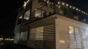 Ein modernes Gebäude mit Balkon, Lichterkette und Garagentor.
