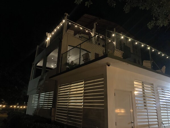 A modern building with a balcony, string lights, and a garage door.