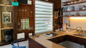 Eine Küche mit Holzvertäfelung, einem Fenster mit Jalousien, einer Kaffeemaschine und einem Spülbecken.