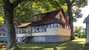 Une maison à deux étages avec un porche, un escalier et une cour clôturée.