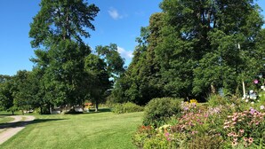 Un espace verdoyant bien entretenu, agrémenté de diverses plantes à fleurs et d’arbres.