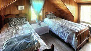Une chambre mansardée chaleureuse avec deux lits, des murs en bois et un plafond en pente.