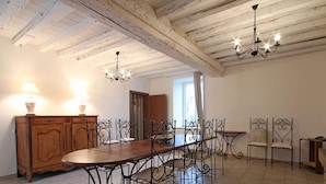A dining area with a wooden table and metal chairs, a wooden cabinet, and a chandelier. - Charming historic cottage, 5 bedrooms, large garden (Coulonges-sur-Sarthe)
