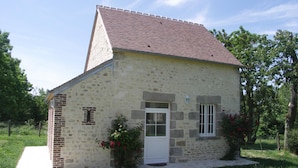 A small stone building with a sloped roof, a brick chimney, and a white door. - Charming historic cottage, 5 bedrooms, large garden (Coulonges-sur-Sarthe)