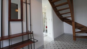 Un escalier avec des marches en bois et une rampe métallique, menant à l’étage supérieur.