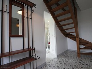 Un escalier avec des marches en bois et une rampe métallique, menant à l’étage supérieur.