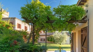 A patio with a table and chairs, surrounded by greenery and a pergola. - Ginestra (Montefalco)