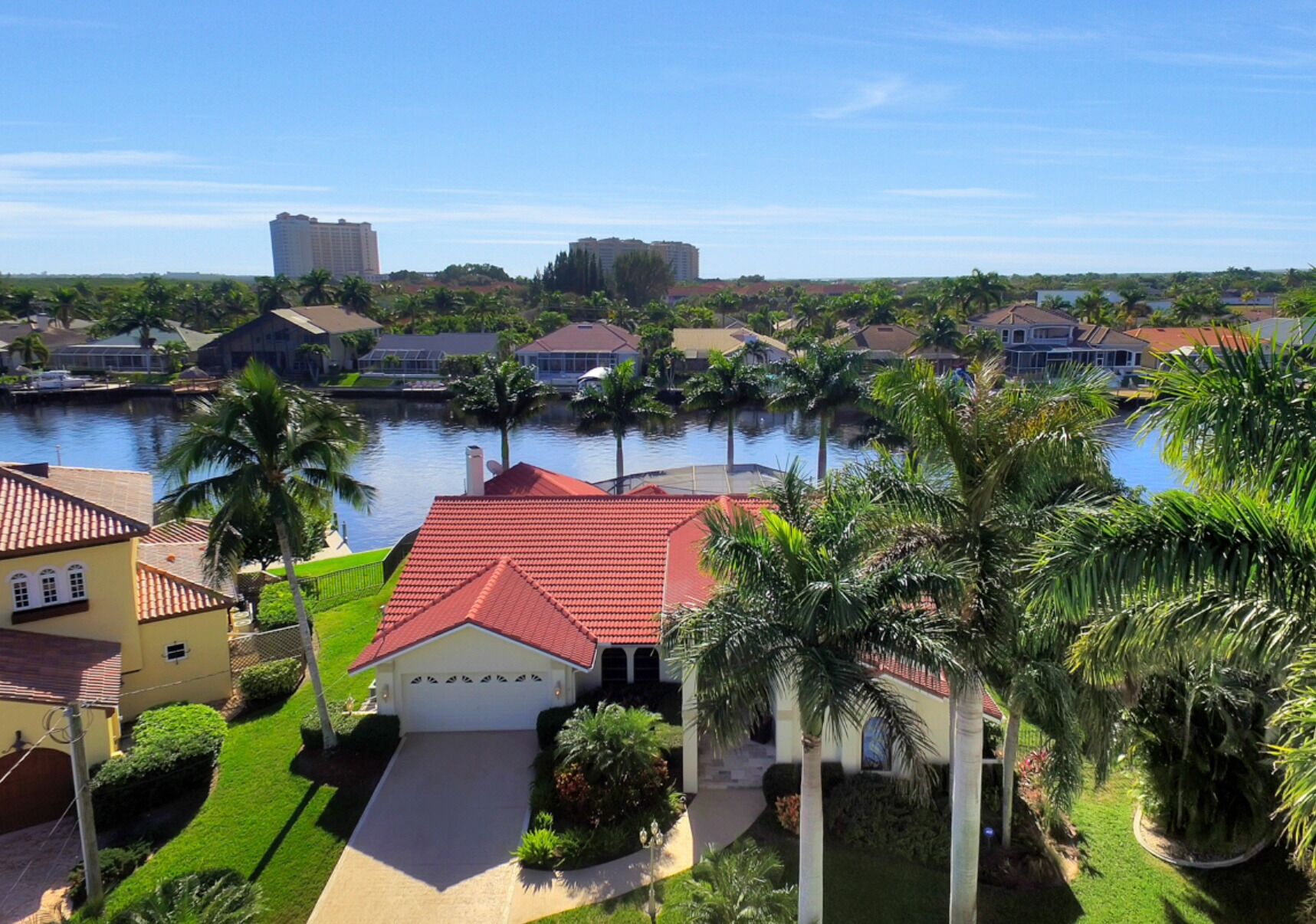 A residential area with houses, a canal, and palm trees.