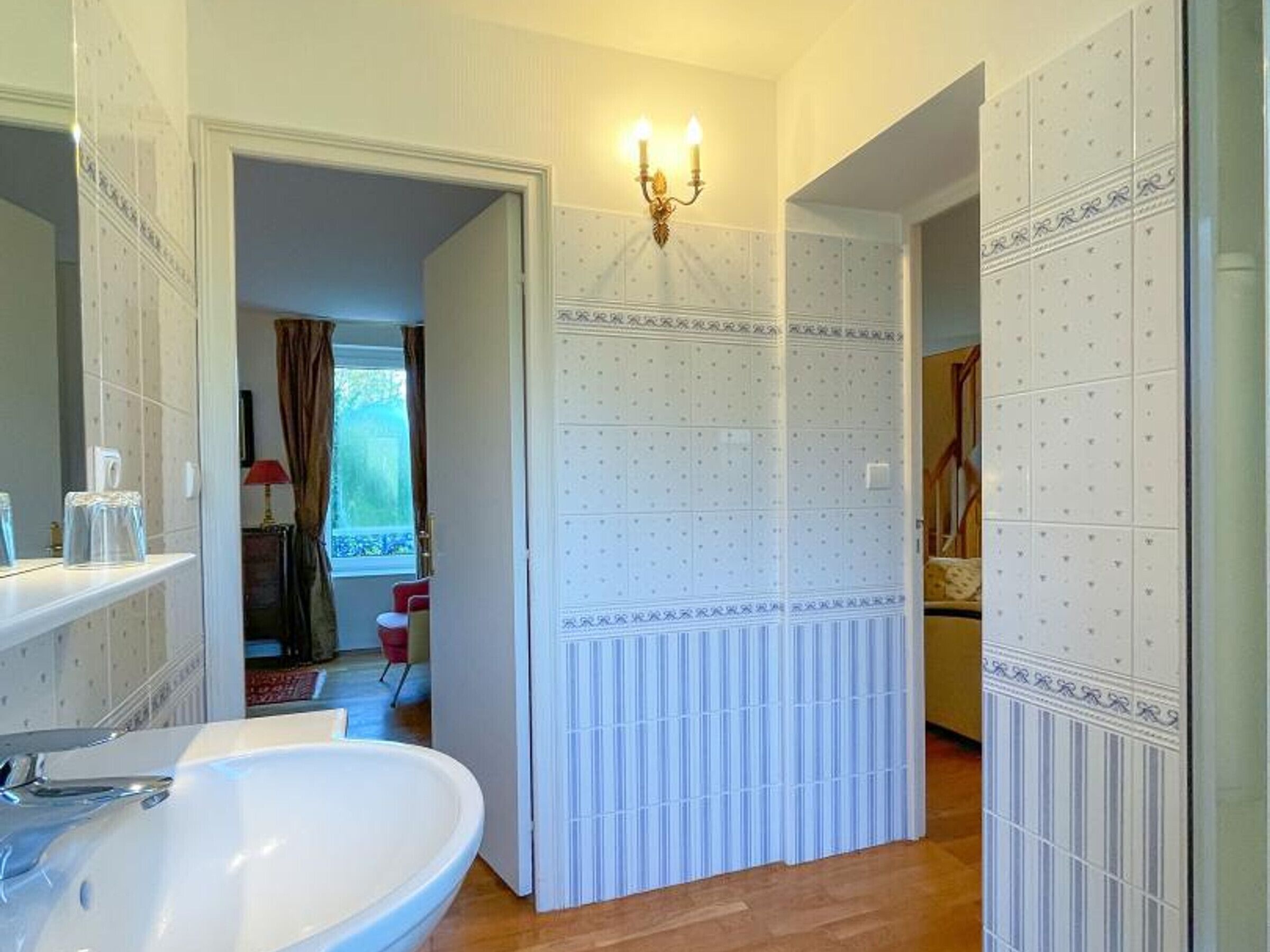 A bathroom with a large white sink, a mirror, and a wall-mounted light fixture.