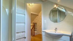 Un baño con un lavamanos blanco, un espejo y una puerta de madera.