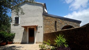 Un bâtiment rustique avec une façade en pierre, une entrée carrelée et une petite fenêtre en arc de cercle.