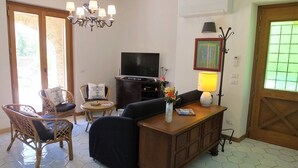 Un salon avec un téléviseur, un lustre, un canapé et une table basse.