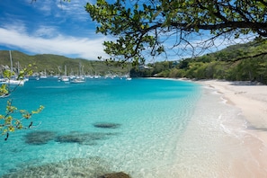 A beach with clear turquoise water, boats, and a sandy shore. - Stunning Beachfront Sunset Flamingo 4 Bedroom Villa sleeps 8 With Private Pool (Richmond)