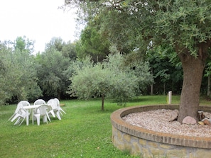 Un jardin doté d’un espace de repos circulaire en pierre, entouré d’arbres et de verdure.