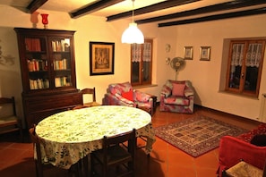 Un salon chaleureux avec une table ronde, deux fauteuils, une bibliothèque et un tapis à motifs.