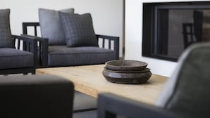 Un salon moderne avec une table basse en bois, deux canapés gris et une grande fenêtre.
