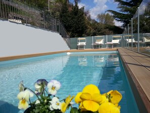 Relax by the pool surrounded by lush trees and comfortable lounge chairs.