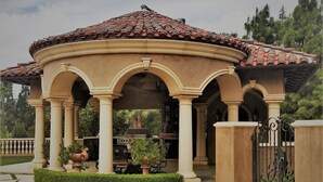 A pavilion with a tiled roof and columns, surrounded by a well-maintained garden and a gated entrance. - CASA VALENTINA-Beautiful Villa Estate (Whittier)