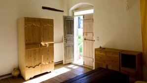 Ein Zimmer mit einem Holzschrank, einem kleinen Tisch und einer zur Außenwelt führenden Tür.