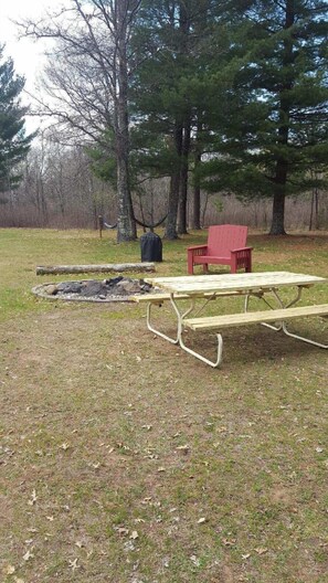 A picnic table and a red chair in a grassy area with trees in the background. - Recreational paradise (Minong)