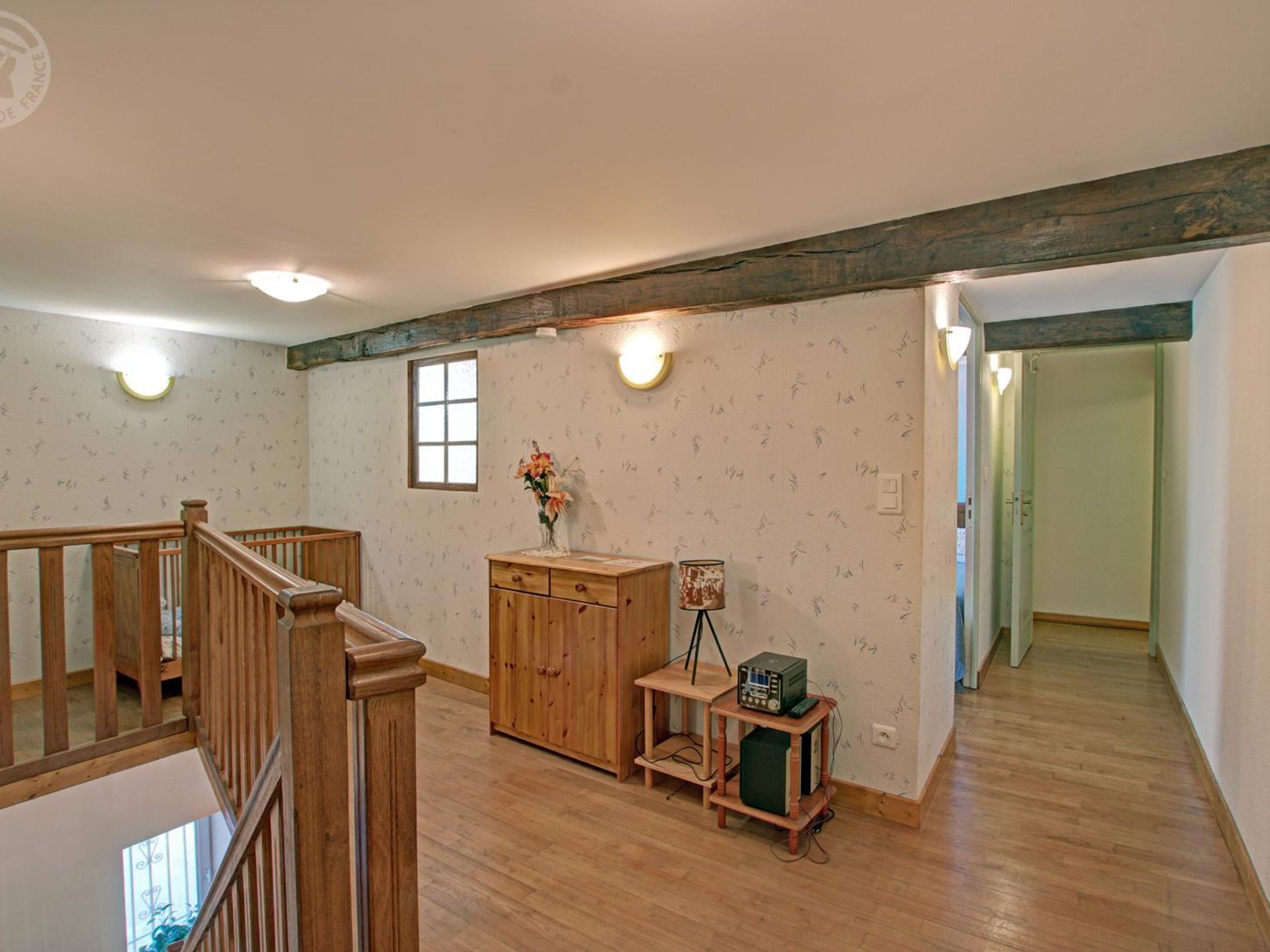 A room with a wooden staircase, a wooden cabinet, a small table with a radio, and a window with a view.