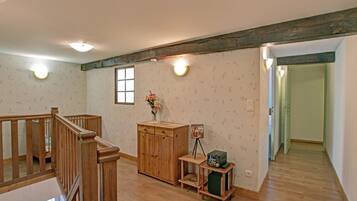 A room with a wooden staircase, a wooden cabinet, a small table with a radio, and a window with a view.