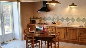 Una cocina con una mesa de comedor lista para cuatro personas, microondas, estufa a gas y armarios de madera.