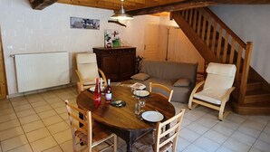 Comedor con mesa de madera, sillas y ventilador de techo. Una escalera conduce a un nivel superior.