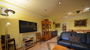 Ein Wohnzimmer mit Flachbildfernseher, Holzmöbeln, einem Ledersofa und einer Vitrine.