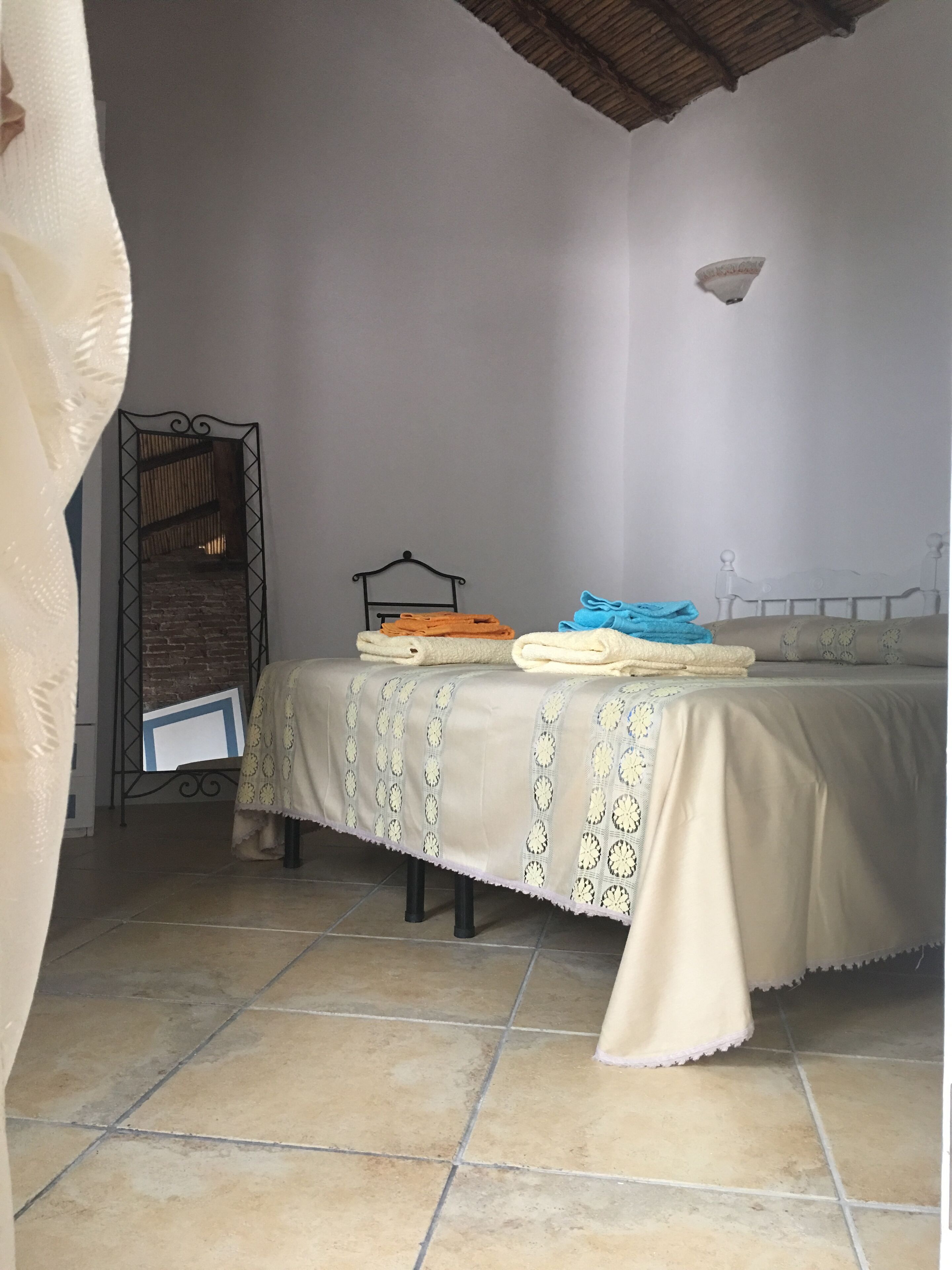 Une chambre à coucher comprenant un lit, une table de chevet, une étagère fixée au mur et une porte avec un rideau.