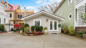 Une maison à deux étages avec un porche à l’avant, un petit jardin et un patio couvert.